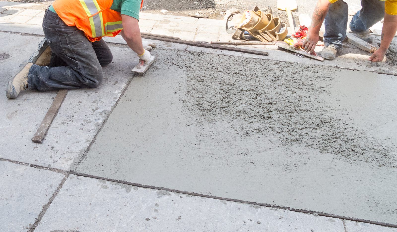 Construction workers finishing concrete surface with trowels and tools