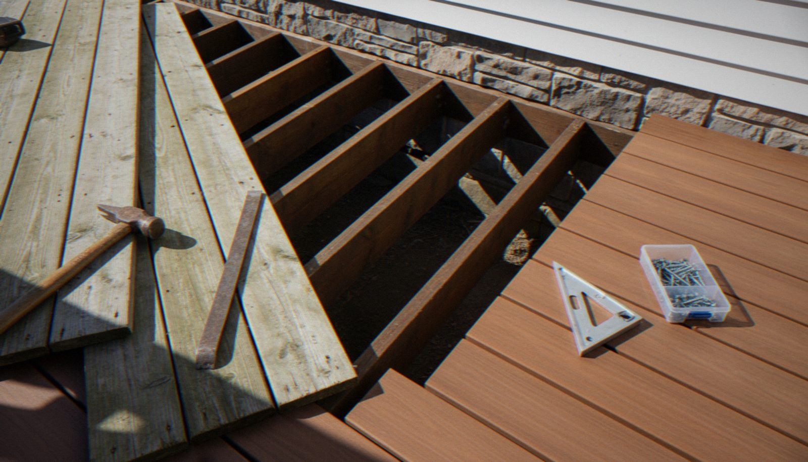 Deck construction with wooden joists, fasteners, and tools on composite decking installation site