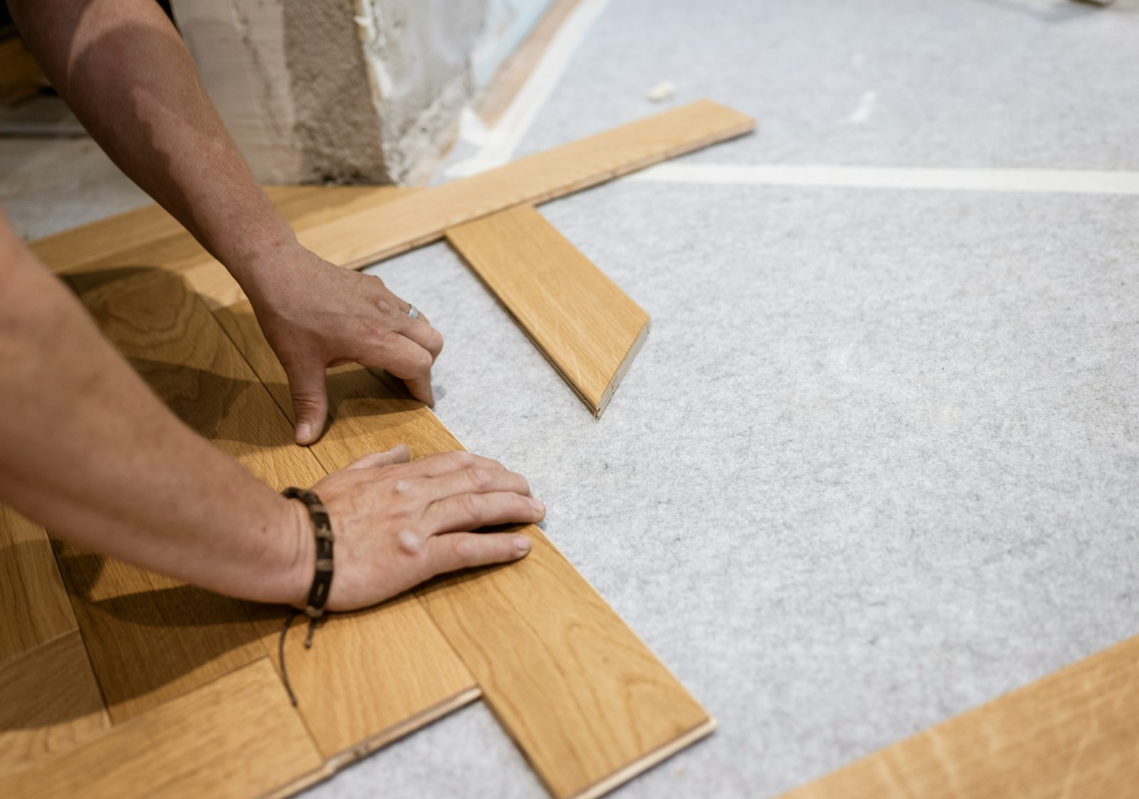 Worker installing laminate flooring planks on concrete subfloor