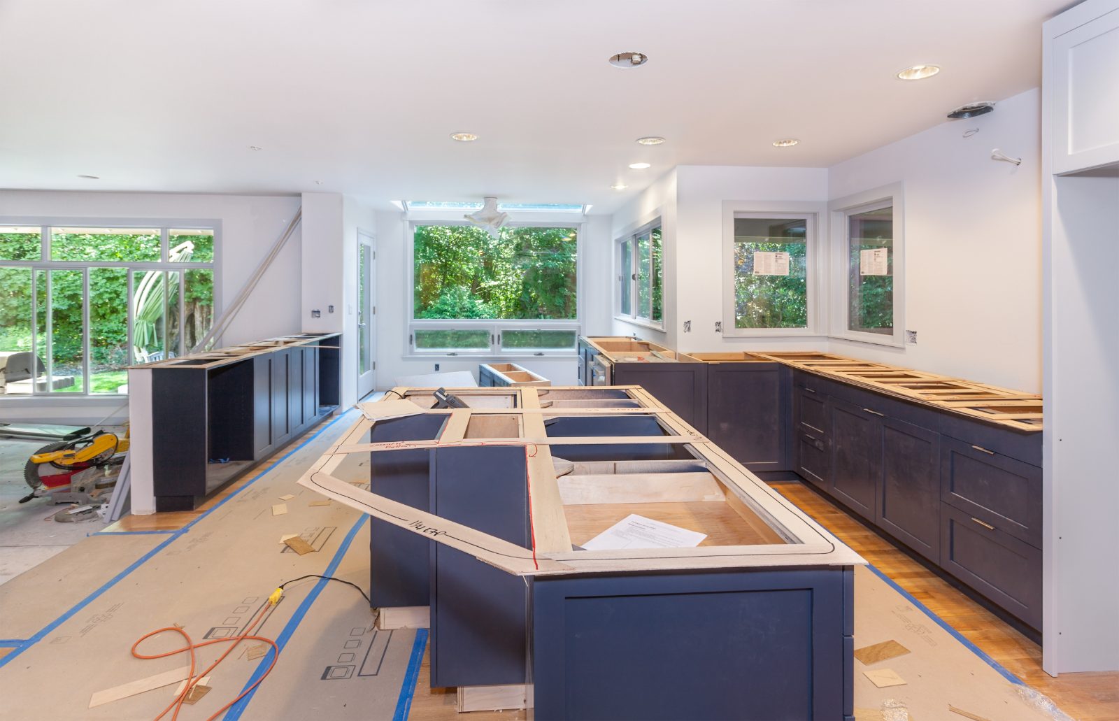 Modern kitchen under construction with dark cabinetry and wooden countertops being installed